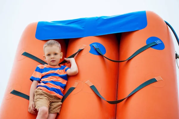 Menino brincando em um playground inflável na praia — Fotografia de Stock