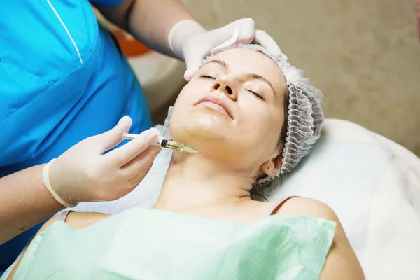 Beautician performs a needle mesotherapy treatment on a woman fa