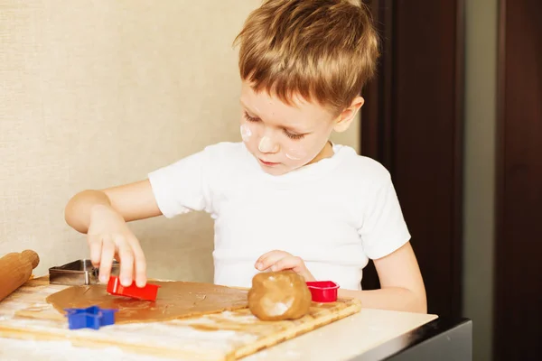 As mãos de crianças fazem pão de gengibre. Pequeno menino cortando biscoitos para — Fotografia de Stock