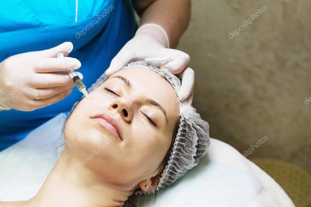 Beautician performs a needle mesotherapy treatment on a woman fa