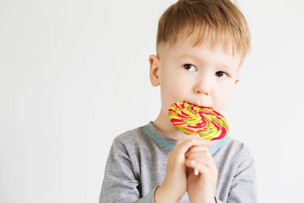 Счастливый ребенок с большой конфеты изолированы на белом фоне — стоковое фото