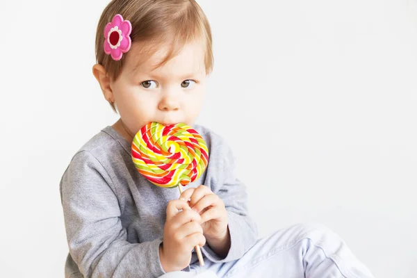 小さな女の子のロリポップを食べるします。大きなおいしい幸せな子供 — ストック写真