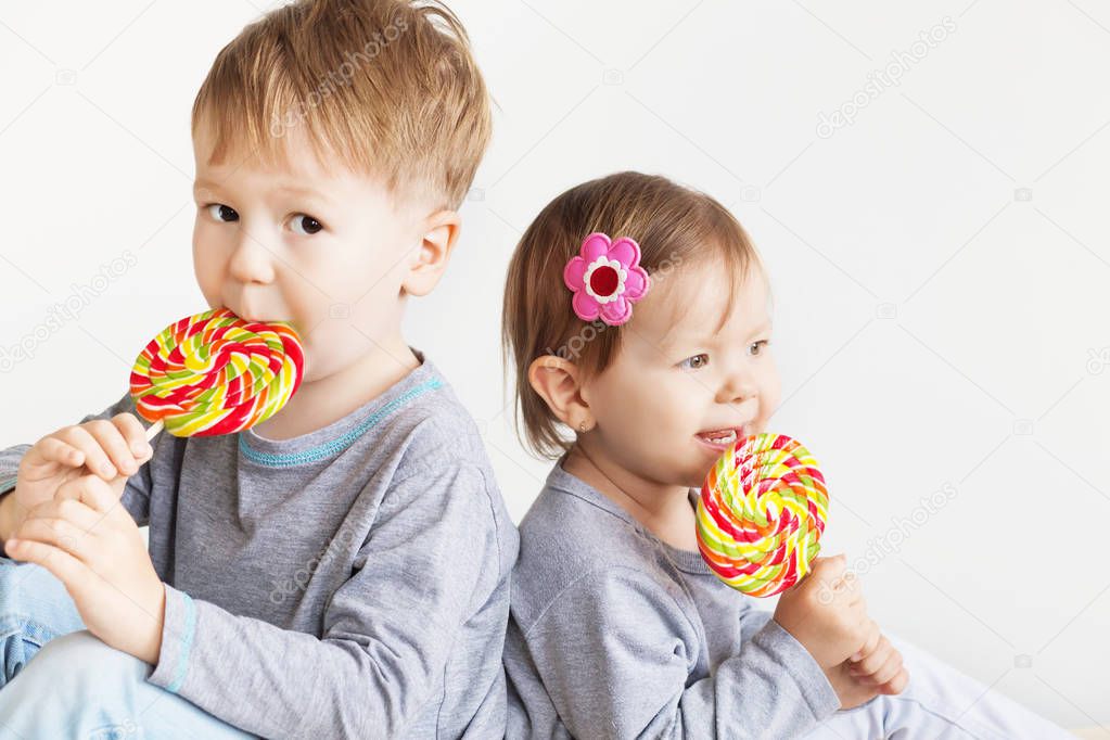 Little children eating lollipops. Happy kids with a big candy