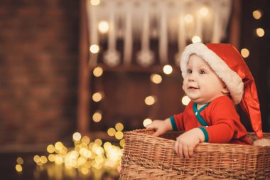 Bir sepet içinde oturup Noel Baba şapkalı küçük oğlu