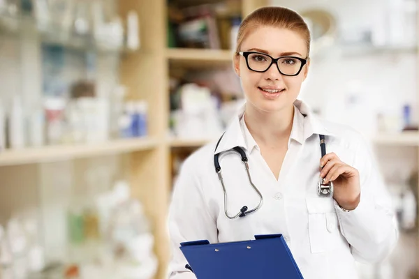 Junge hübsche Ärztin in weißer Uniform auf verschwommenem Medikament — Stockfoto