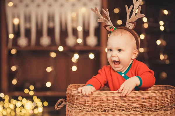 Pequeño niño en cuernos de reno sentado en una canasta de mimbre — Foto de Stock