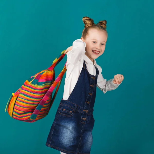 Zabawny uśmiechający się mała dziewczynka z f skoki i o plecak duży — Zdjęcie stockowe