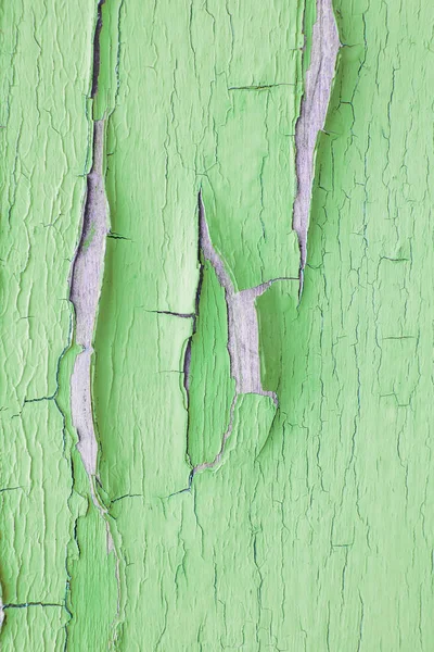 Cracking and peeling green paint on a wall. Vintage wood background with peeling paint. Old board with Irradiated paint