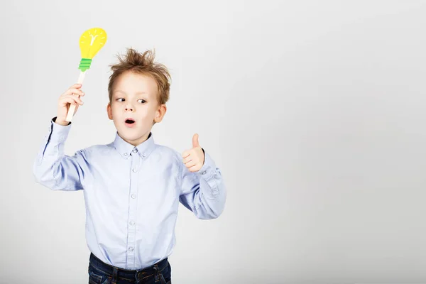 Cute little school boy with yellow paper lightbulb against a whi — Stock Photo, Image