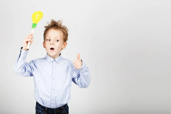 Mignon petit écolier avec jaune ampoule en papier contre un whi — Photo