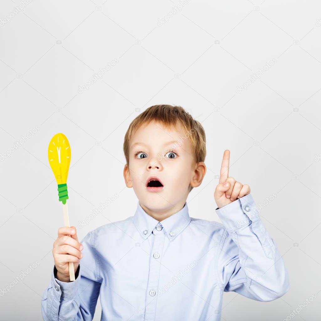 Cute boy with yellow paper lightbulb against a white background.