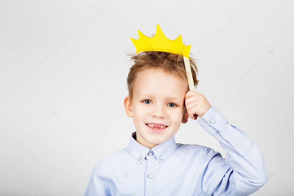 Portrait of a cute little school boy with yellow paper crown aga