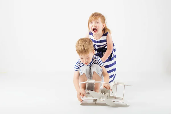Malé děti si hrají s papírové hračky letounu sedí na f — Stock fotografie