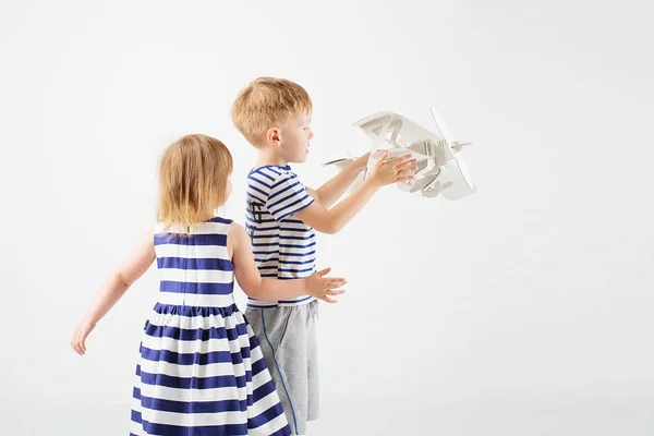 Küçük çocuklar karşı beyaz bir kağıt oyuncak uçak ile oyun — Stok fotoğraf