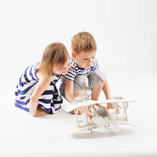 Petits enfants jouant avec jouet en papier avion assis sur le f — Photo