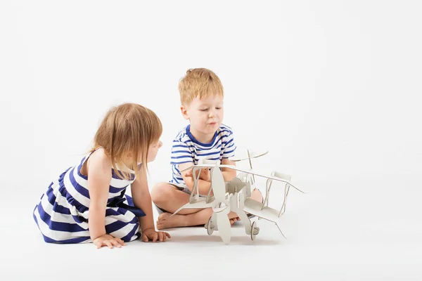 Pequeños niños jugando con un avión de juguete de papel sentado en la f — Foto de Stock