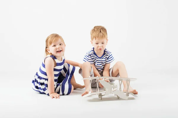 Pequeños niños jugando con un avión de juguete de papel sentado en la f — Foto de Stock