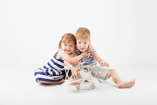 Pequeños niños jugando con un avión de juguete de papel sentado en la f — Foto de Stock