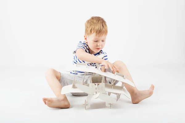 Junge spielt mit Spielzeugflugzeug aus Papier, das auf dem Boden sitzt — Stockfoto