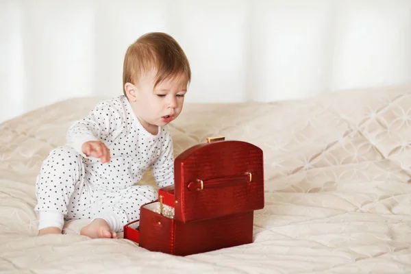 Menina bebê brincando com jóias de sua mãe sentado em uma cama em — Fotografia de Stock