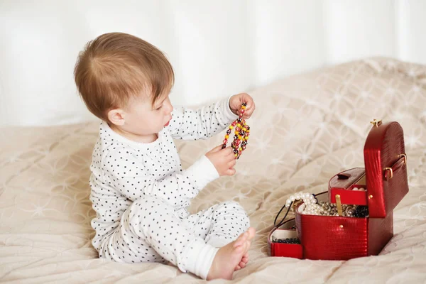 Niña jugando con las joyas de su madre sentada en una cama en — Foto de Stock