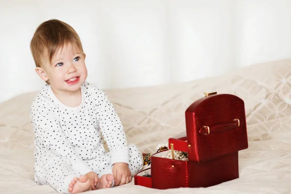 Bayi perempuan bermain dengan perhiasan ibunya duduk di tempat tidur di — Stok Foto