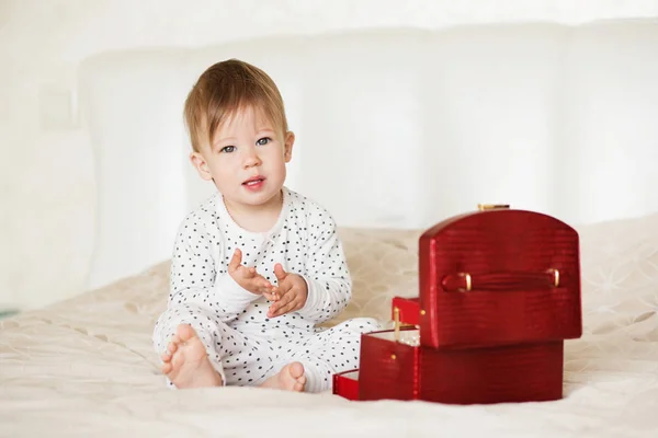 Menina bebê brincando com jóias de sua mãe sentado em uma cama em — Fotografia de Stock