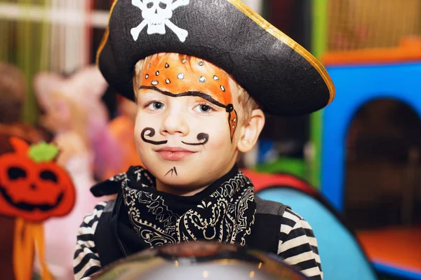 Halloween party. A little boy in a pirate costume and a makeup on his face is having a good time at the Halloween party. Face painting kids.