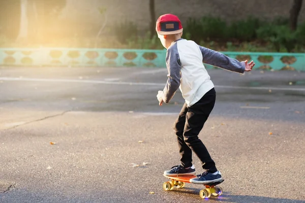 Маленький міський хлопчик з копійки скейтборд. Молодий хлопець їде в — стокове фото