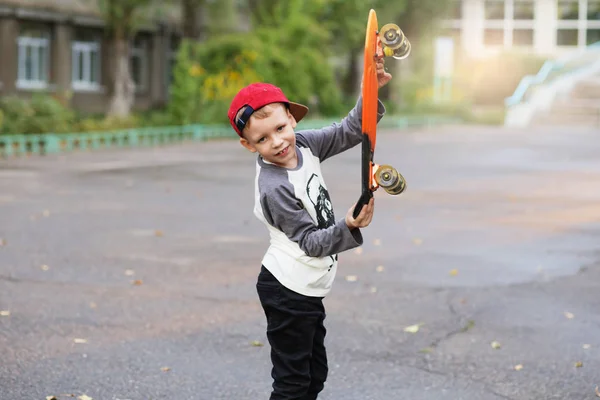 Un ragazzino di città con uno skateboard da due soldi. Giovane bambino cavalcando in th — Foto Stock