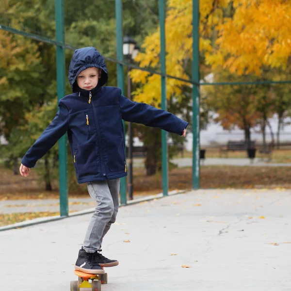 Little urban boy with a penny skateboard. Kid skating in an autu — Stock Photo, Image