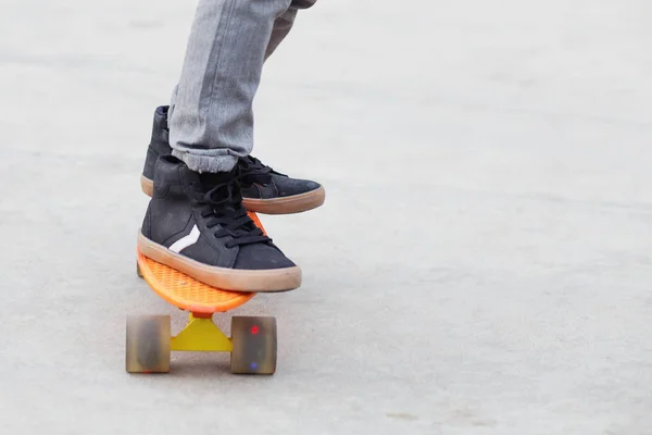 Menino de pé em um skate laranja ao ar livre. Fechar ima — Fotografia de Stock