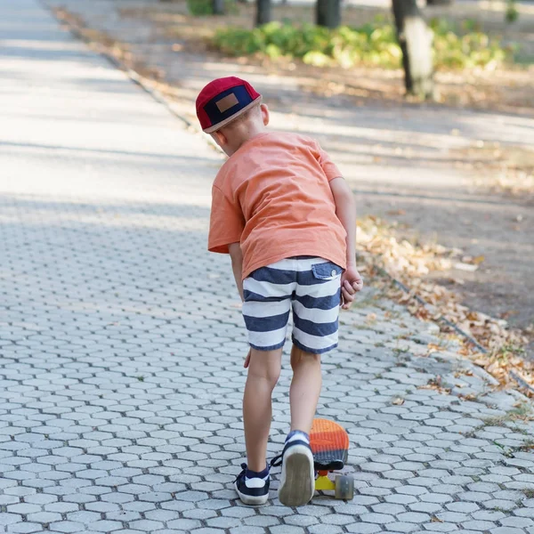 Little urban boy with a penny skateboard. Kid skating in a summe — Stock Photo, Image