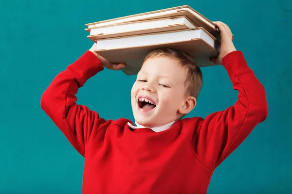 Glada leende liten skola pojke med stora böcker på hans huvud ha — Stockfoto