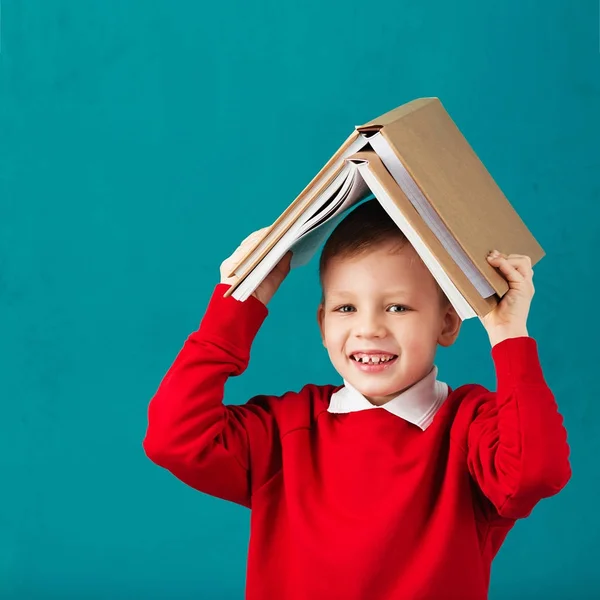 Cheerful smiling little school boy in red sweatshirt holding big — Stock Photo, Image