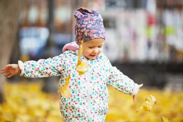 Glad urban liten flicka promenader i höst stadspark. — Stockfoto