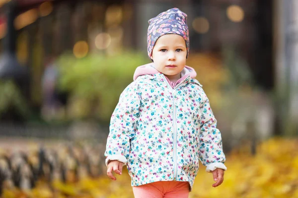 Glad urban liten flicka promenader i höst stadspark. — Stockfoto