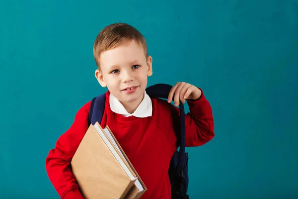 Fröhlich nachdenklicher kleiner Schuljunge in Schuluniform mit Bac — Stockfoto