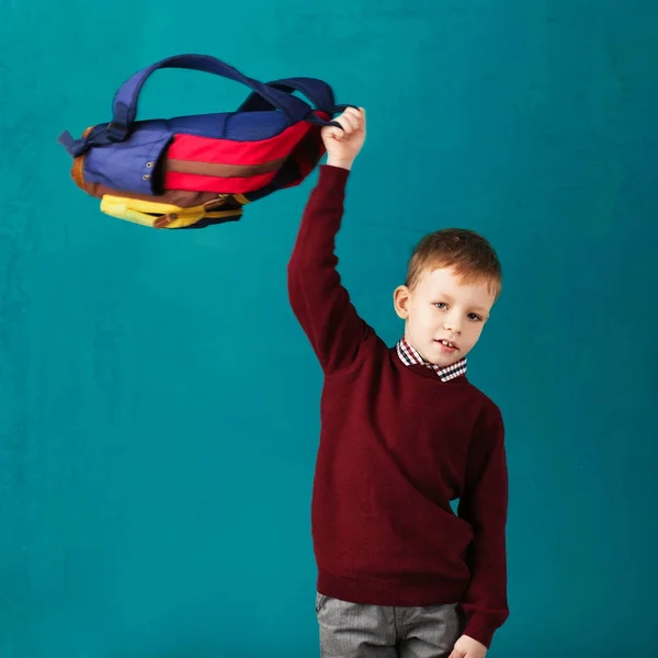 Веселый вдумчивый маленький школьник в школьной форме с большой — стоковое фото