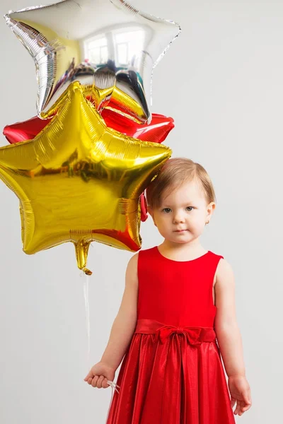 Pequena menina segurando balões na forma de estrelas. Jovem gi — Fotografia de Stock