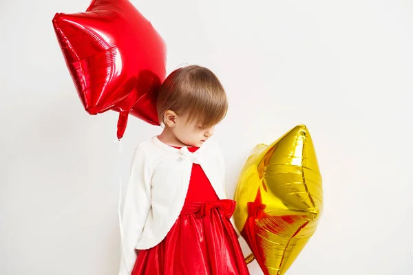 Menina bonito brincando com balões em forma de estrela na frente de w — Fotografia de Stock