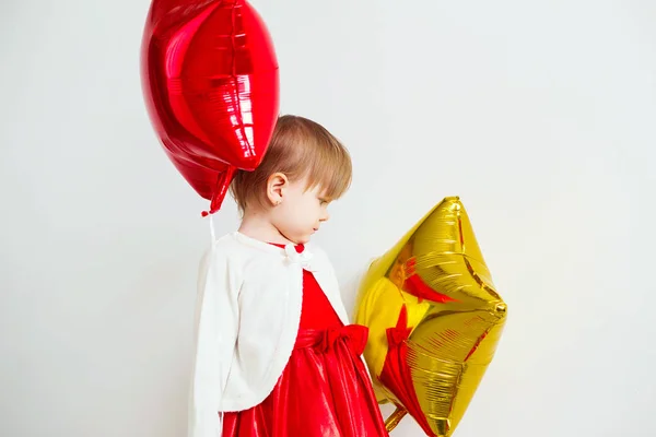 Linda niña jugando con globos en forma de estrella en frente de w — Foto de Stock