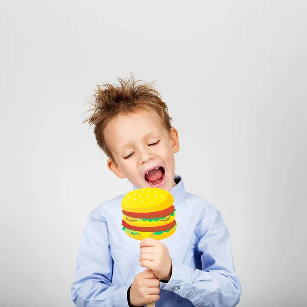 Carino poco scuola ragazzo con falso carta hamburger contro un bianco ba — Foto Stock