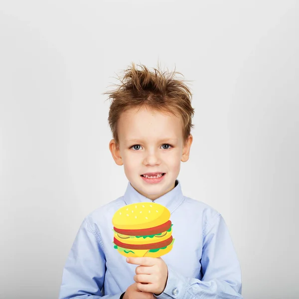 Lindo niño de la escuela con hamburguesa de papel falso contra una ba blanca — Foto de Stock