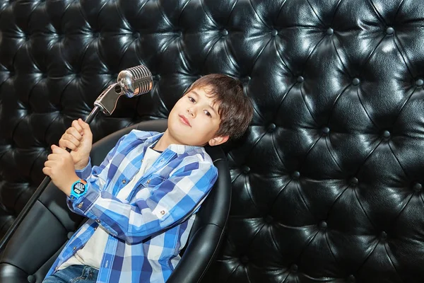 Canto menino com um microfone em um rack — Fotografia de Stock