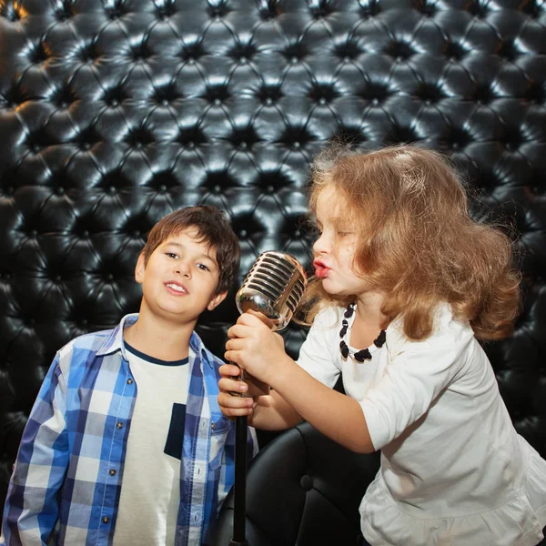 Cantar crianças pequenas com um microfone em um rack — Fotografia de Stock