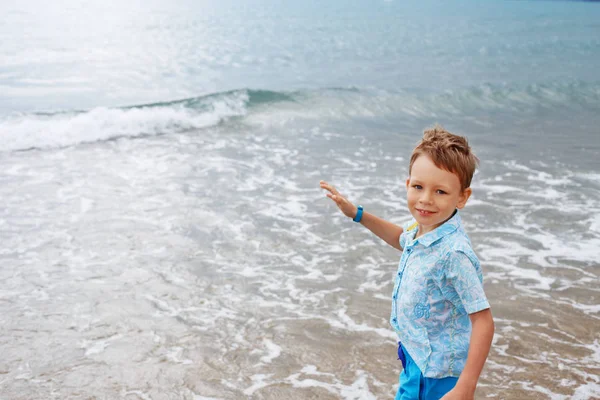 Niño pequeño en camisa y pantalones cortos en la arena de la playa. Pequeño niño tiene — Foto de Stock