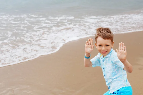 Niño pequeño en camisa y pantalones cortos en la arena de la playa. Pequeño niño tiene — Foto de Stock