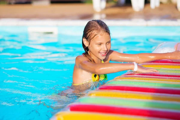 Niña jugando y divirtiéndose en la piscina con colchoneta de aire — Foto de Stock