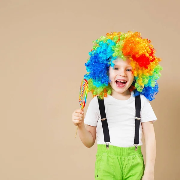 Felice clown ragazzo in grande parrucca colorata. Festeggiamo! Ragazzo divertente cl — Foto Stock